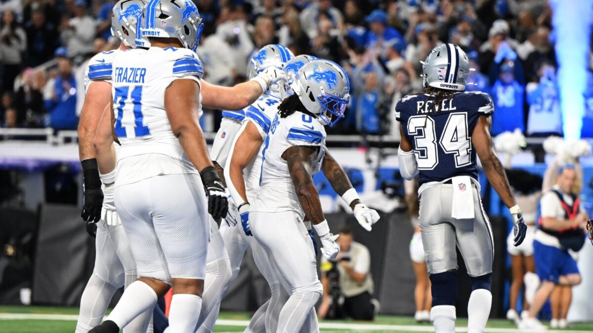 Jahmyr Gibbs surrounded by teammates after a touchdown