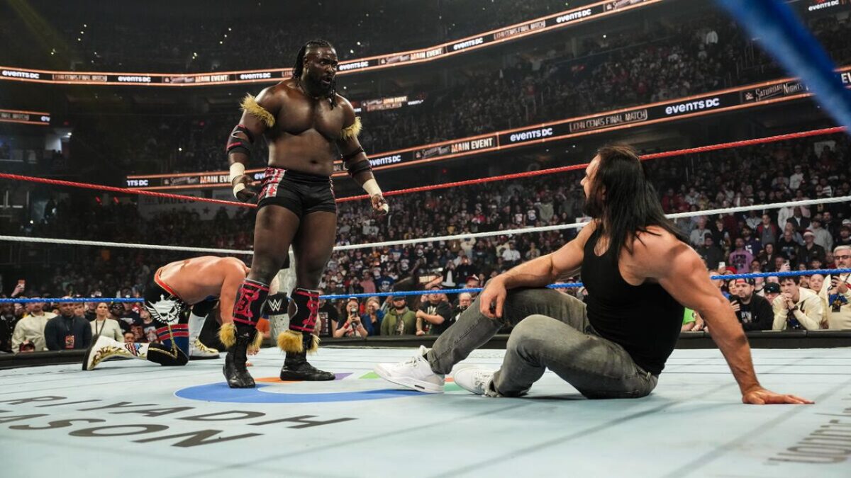 Oba Femi looking down at Drew McIntyre