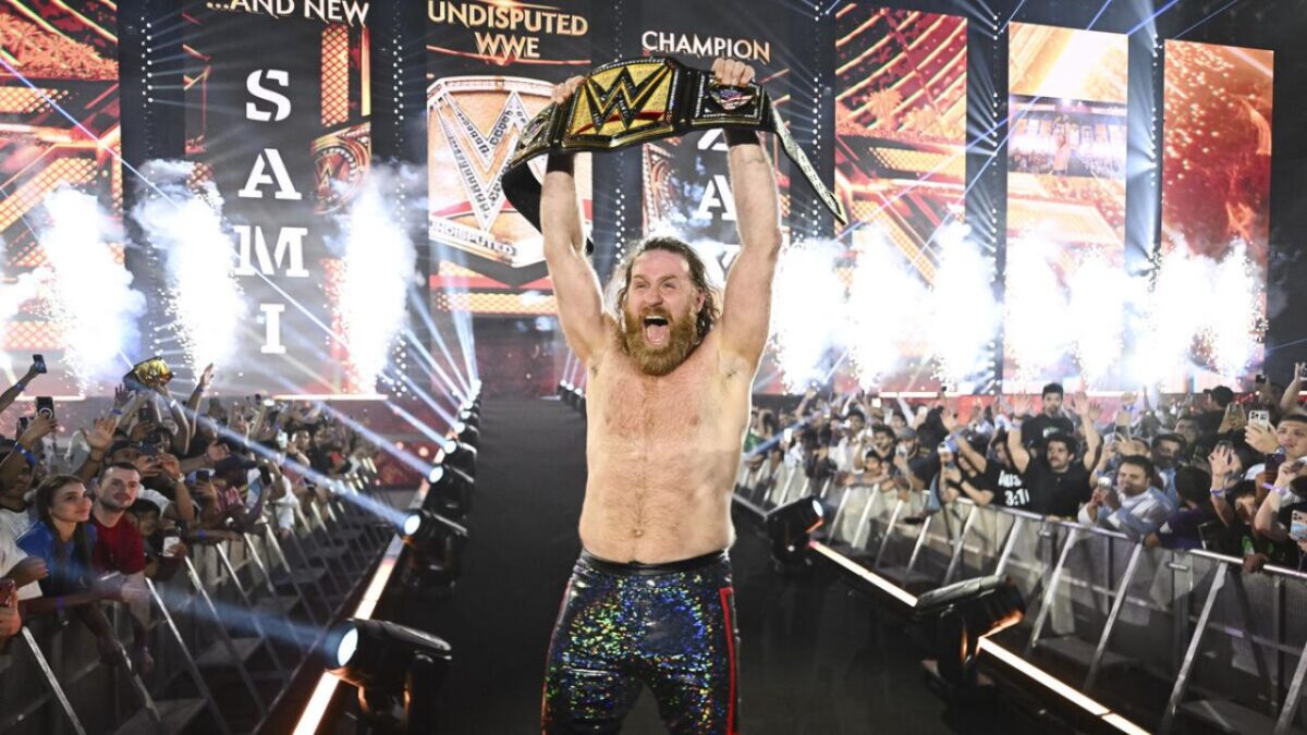 Sami Zayn's Transitional WWE Champion Discourse Shot Down by JBL 1 Sami Zayn posing with the Undisputed WWE Championship